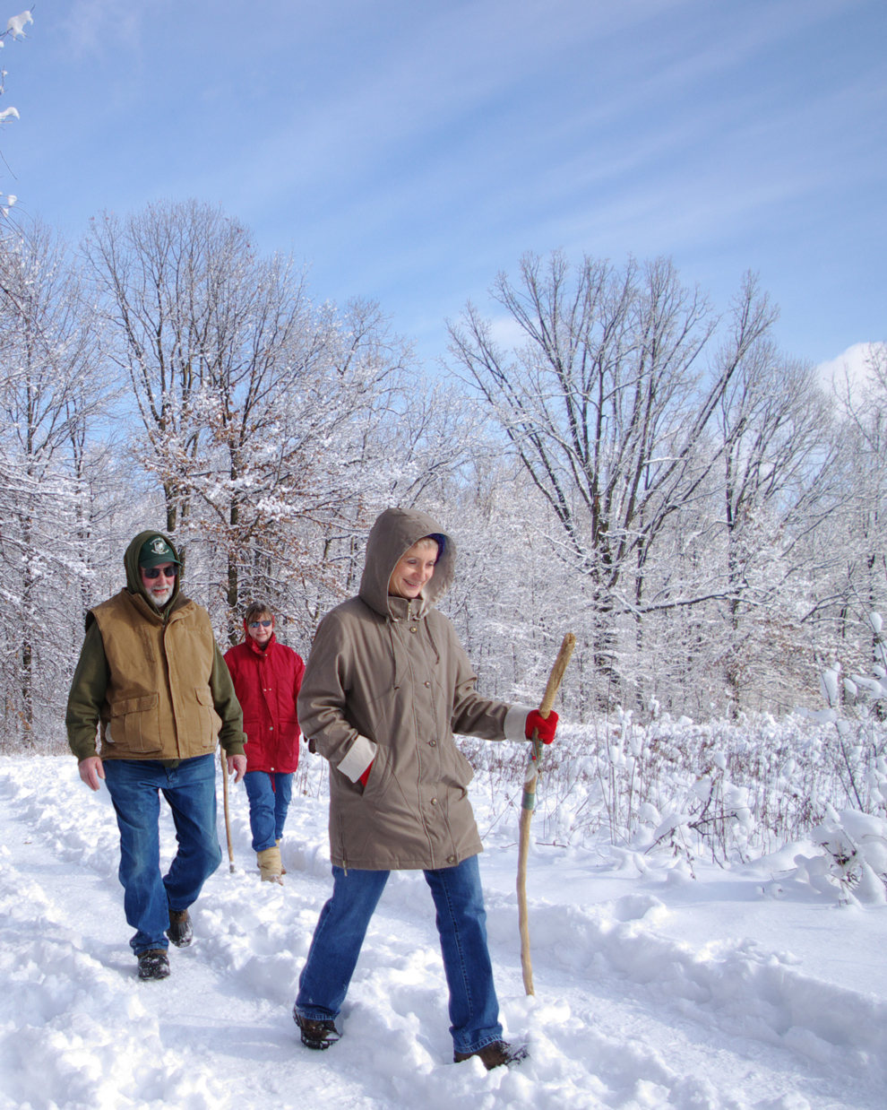 Three hikers walk along a snowy trail at Blendon Woods