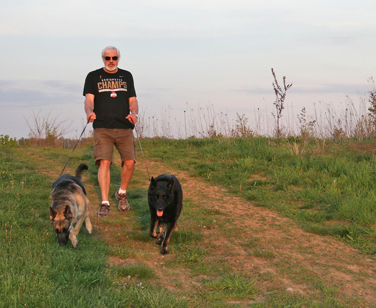 Visitor walks his dogs on the Kestrel Trail at Walnut Woods