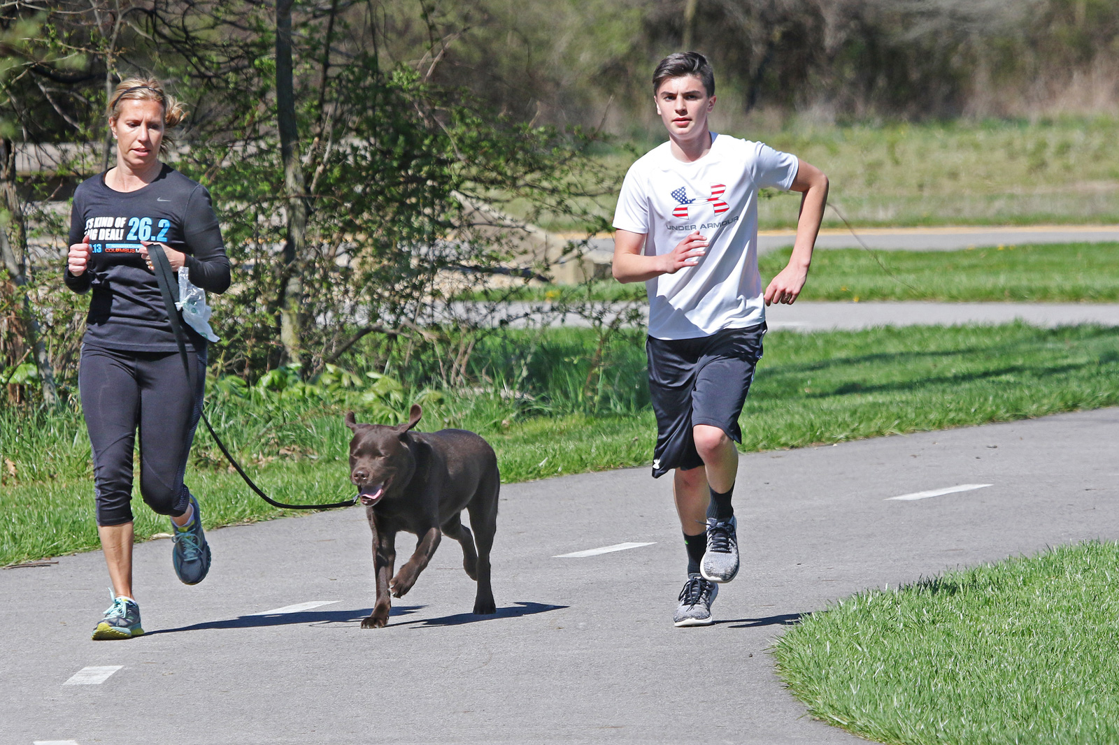 Park visitor and son run on the Beech Woodland Trail at Rocky Fork with their labrador.