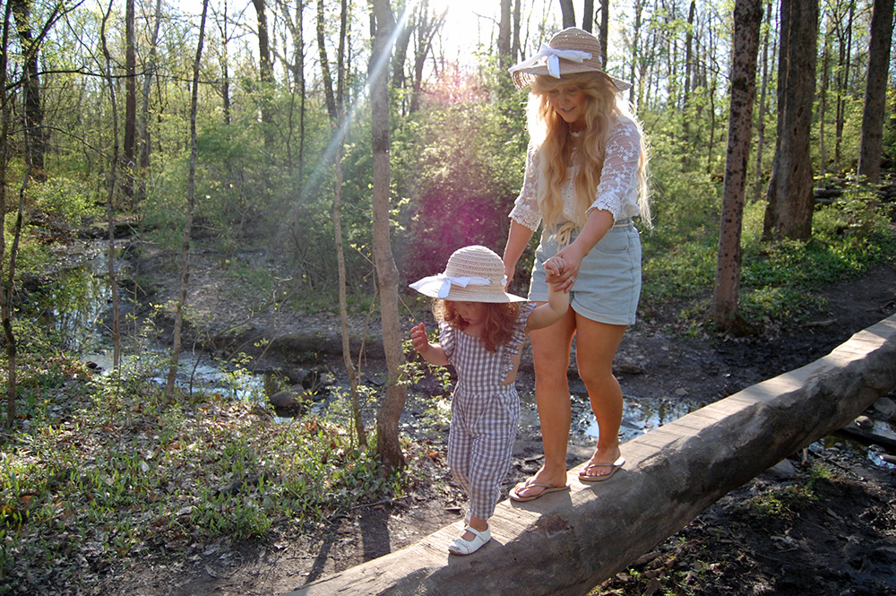 A woman and child walk across a log in the natural play area at Blendon Woods Metro Park. 
