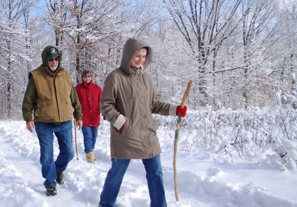 Three hikers walk along a snowy trail at Blendon Woods