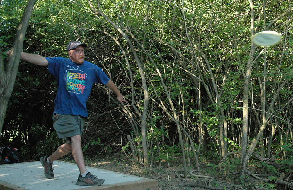 A man throws a disc at the new disc golf course at Scioto Grove.