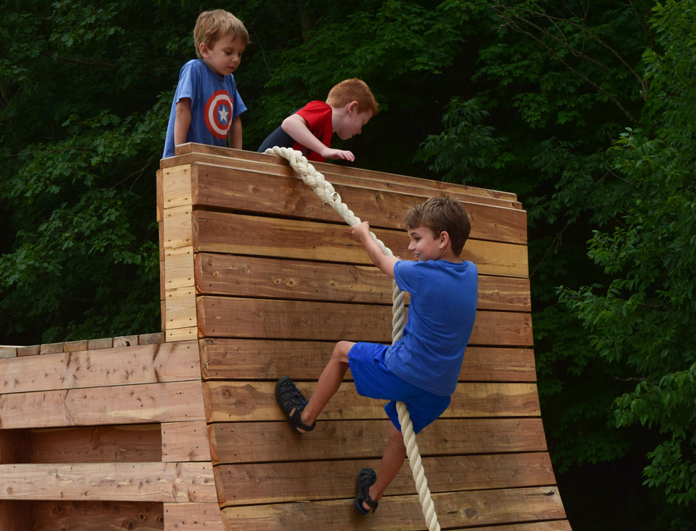 A child climbs the wall on one of the play structures at Glacier Ridge.