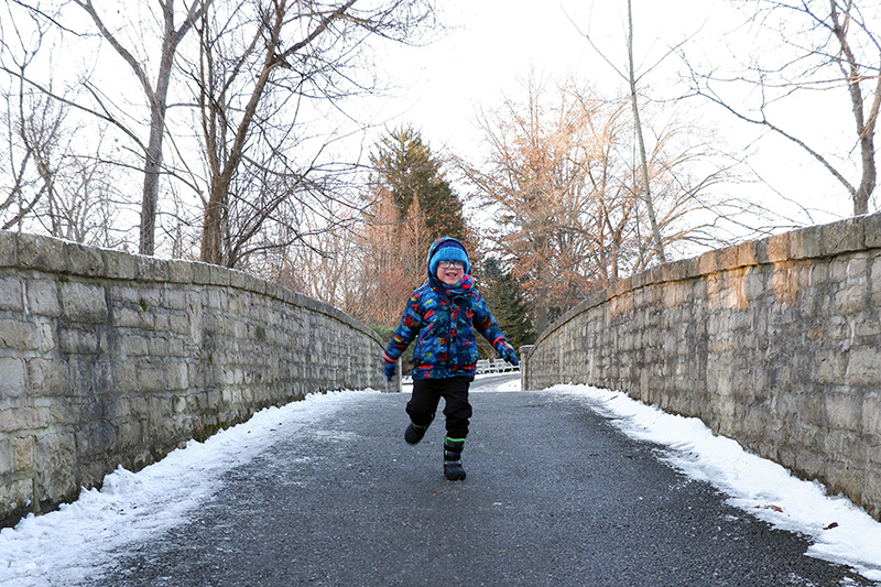 A child runs across the bridge near the Brookwood Trail during the winter hike at Inniswood Metro Gardens.