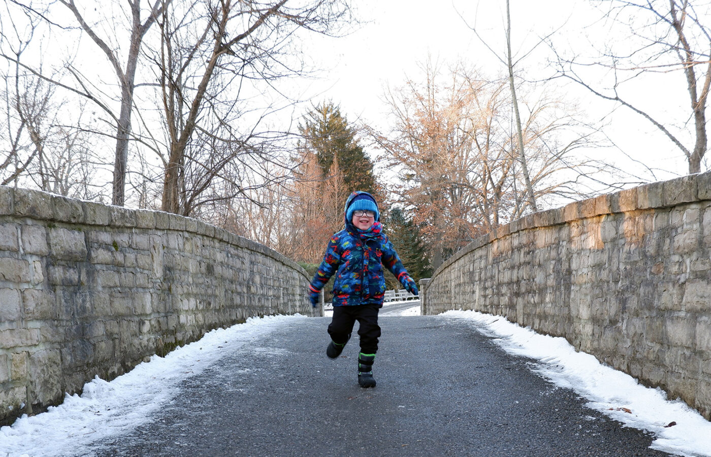 A child runs across the bridge near the Brookwood Trail during the winter hike at Inniswood Metro Gardens.