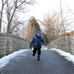 A child runs across the bridge near the Brookwood Trail during the winter hike at Inniswood Metro Gardens.